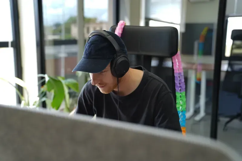 Seppe Nees met een koptelefoon op, aan het werk aan zijn bureau
